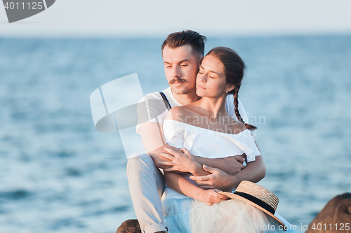 Image of Happy young romantic couple relaxing on the beach and watching the sunset