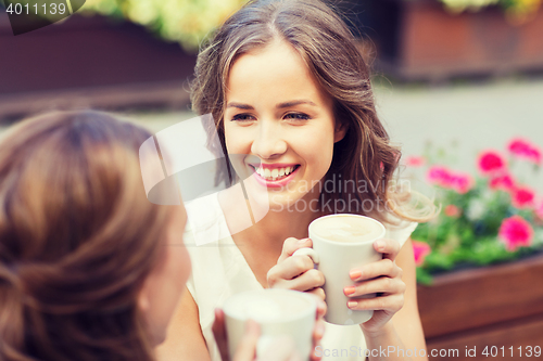 Image of smiling young women with coffee cups at cafe