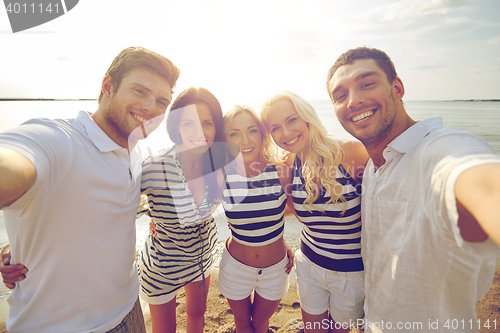 Image of happy friends on beach and taking selfie