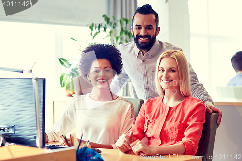 Image of happy creative team with computer in office