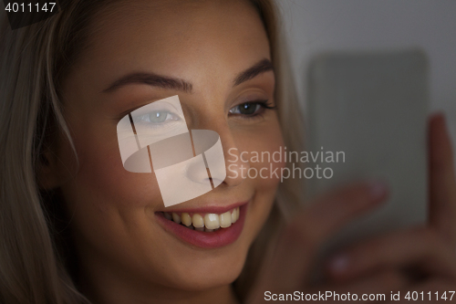 Image of happy smiling young woman with smartphone at night