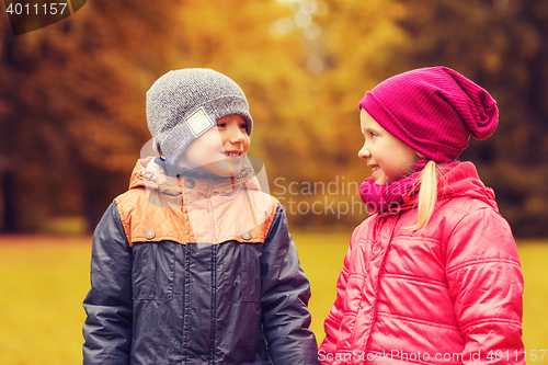 Image of happy little girl and boy talking in autumn park