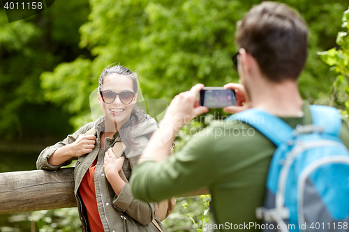 Image of couple with backpacks taking picture by smartphone