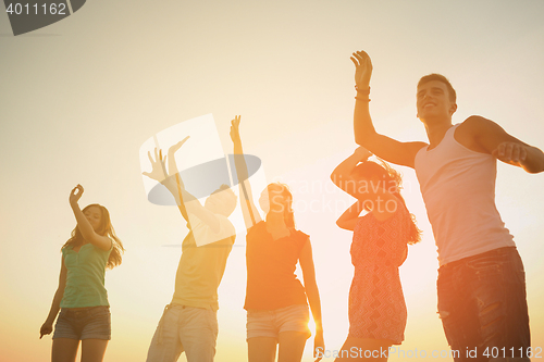Image of smiling friends dancing on summer beach