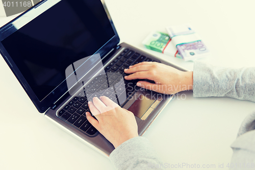 Image of close up of woman hands with laptop and money