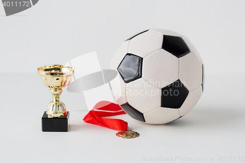 Image of close up of football ball, golden cup and medal