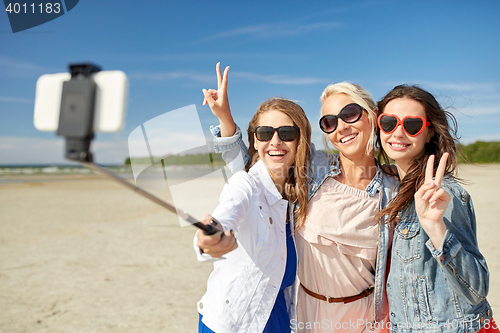 Image of group of smiling women taking selfie on beach