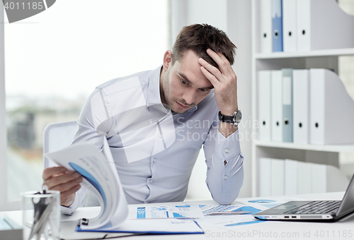 Image of stressed businessman with papers at office