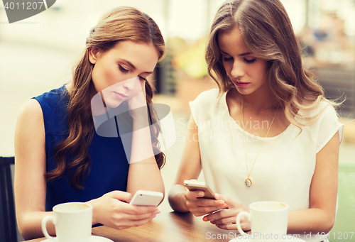 Image of women with smartphones and coffee at outdoor cafe