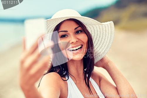 Image of smiling young woman taking selfie with smartphone