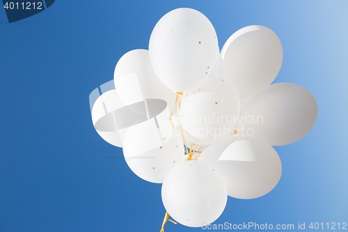 Image of close up of white helium balloons in blue sky