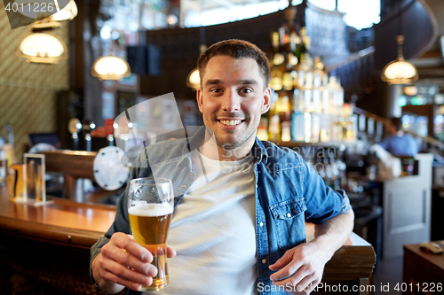 Image of happy man drinking draft beer at bar or pub