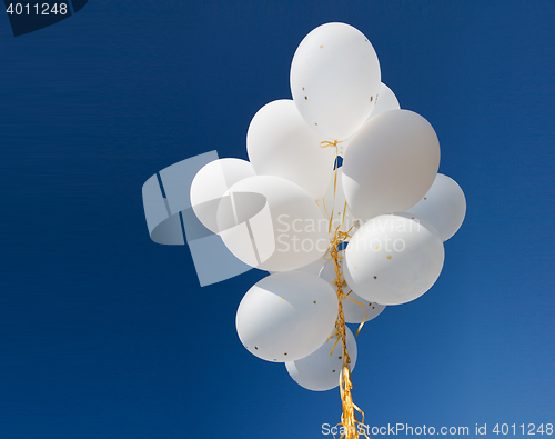 Image of close up of white helium balloons in blue sky