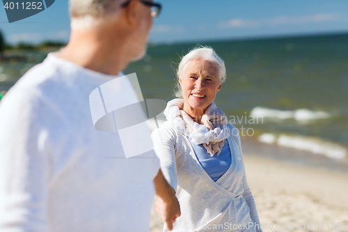 Image of happy senior couple holding hands on summer beach