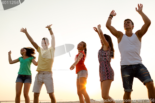 Image of smiling friends dancing on summer beach