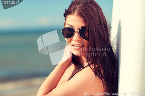 Image of smiling young woman with surfboard on beach