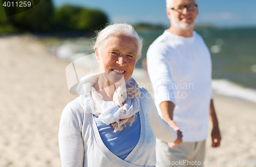 Image of happy senior couple holding hands on summer beach