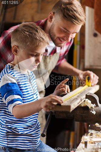 Image of father and son with ruler measure wood at workshop