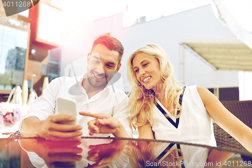 Image of happy couple with smatphone at restaurant terrace