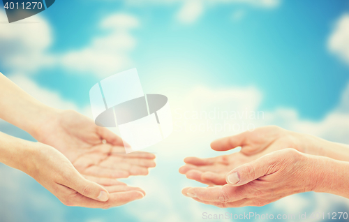 Image of close up of senior and young woman hands