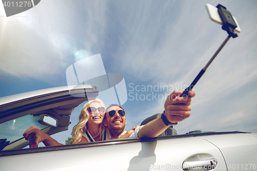 Image of happy couple in car taking selfie with smartphone