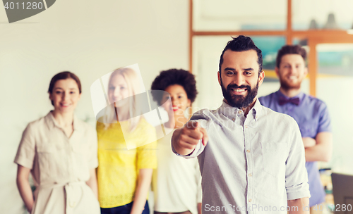 Image of happy man pointing finger at you over office team