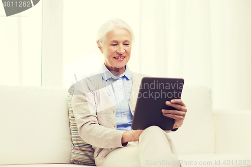 Image of happy senior woman with tablet pc at home