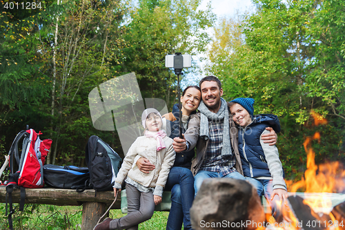 Image of family with smartphone taking selfie near campfire