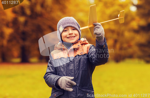 Image of happy little boy playing with toy plane outdoors