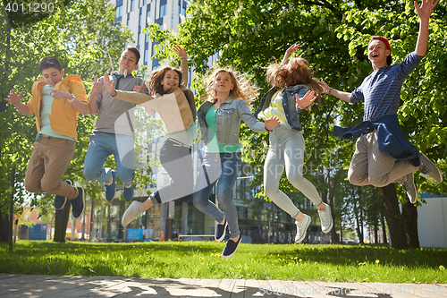 Image of happy teenage students or friends jumping outdoors