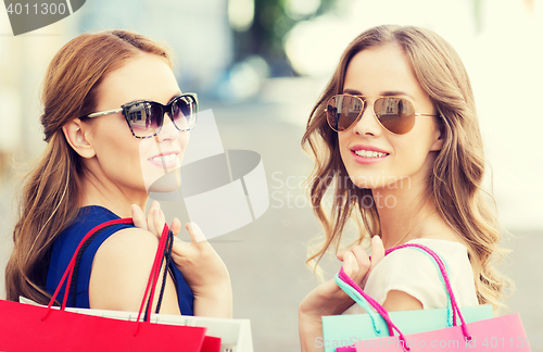 Image of happy young women with shopping bags in city
