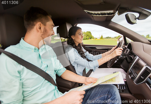 Image of happy man and woman with road map driving in car