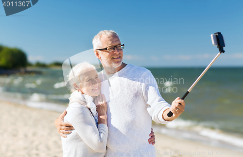 Image of happy senior couple hugging on summer beach