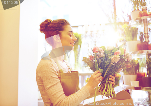 Image of smiling florist woman making bunch at flower shop