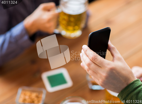 Image of close up of friends with smartphone and beer