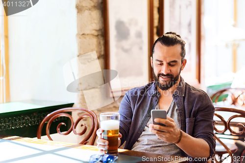 Image of man with smartphone drinking beer at bar or pub