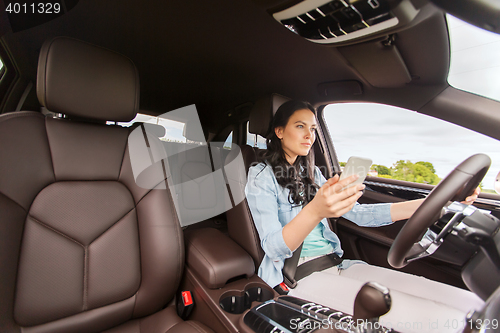 Image of happy woman driving car with smarhphone