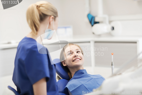 Image of happy female dentist with patient girl at clinic