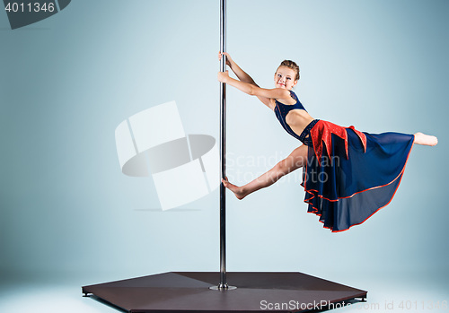 Image of The strong and graceful young girl performing acrobatic exercises on pylon