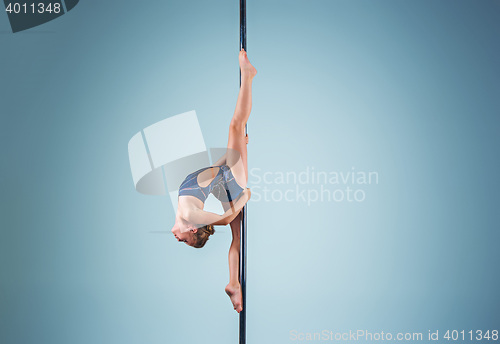 Image of The strong and graceful young girl performing acrobatic exercises on pylon