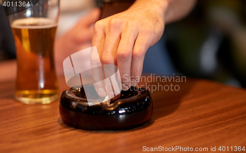 Image of close up of hand extinguish cigarette in ashtray