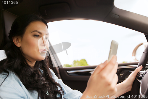 Image of happy woman driving car with smarhphone