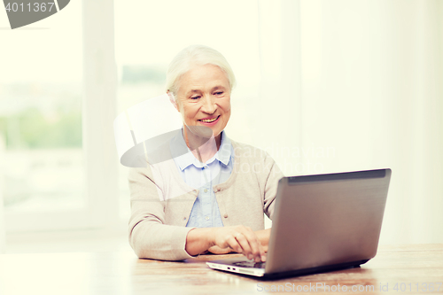Image of happy senior woman with laptop at home