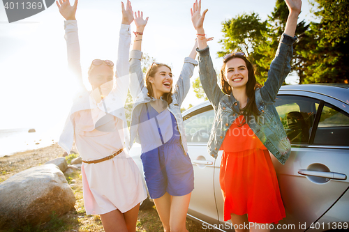 Image of happy teenage girls or women near car at seaside