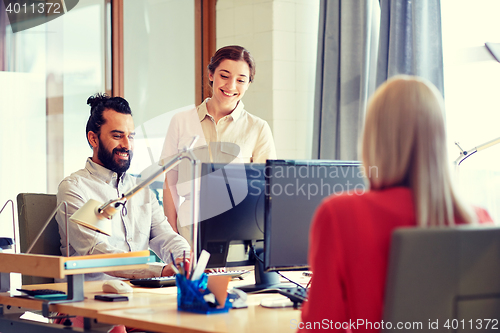 Image of happy creative team with computers in office