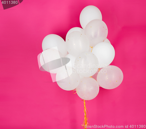 Image of close up of white helium balloons over pink