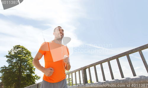 Image of happy man with earphones running outdoors