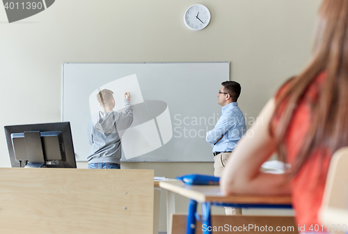 Image of teacher and student writing on board at school