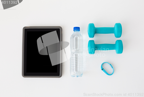 Image of tablet pc, dumbbells, fitness tracker and bottle