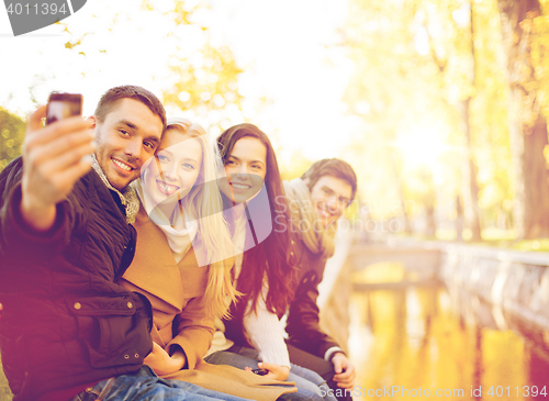 Image of group of friends with photo camera in autumn park